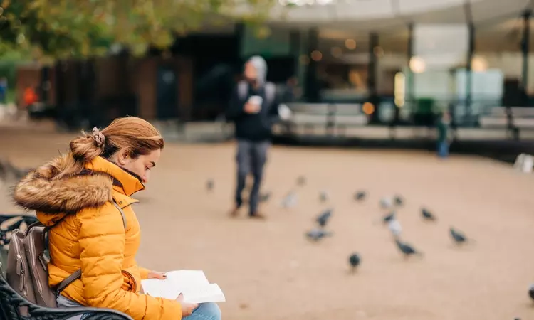 Woman reading a book on a park bench