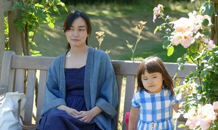 A mum and daughter sitting on a bench with roses